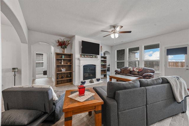 3512 Tunnel Ave, Aubrey, TX 76227 - living area featuring arched walkways, ceiling fan, and a glass covered fireplace