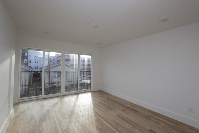 spare room with baseboards and wood finished floors