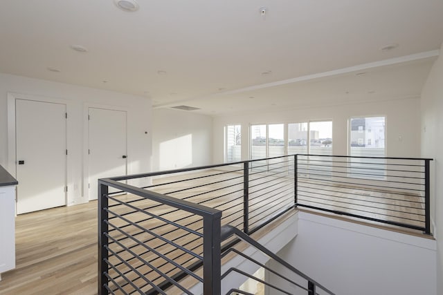 hallway with an upstairs landing and light wood-style floors