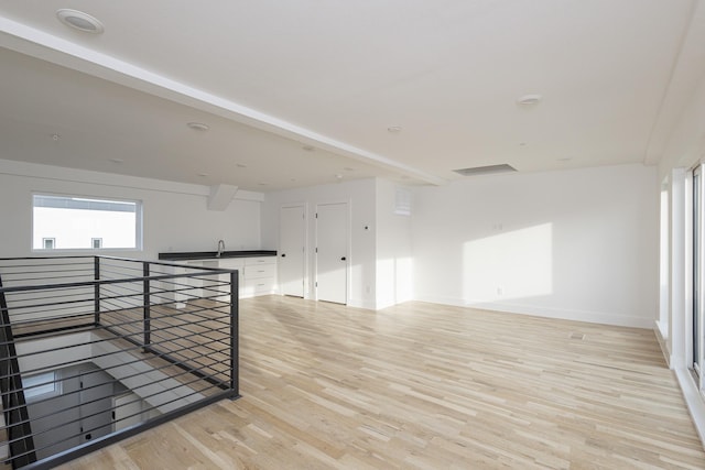 unfurnished room featuring light wood-type flooring, a healthy amount of sunlight, and baseboards