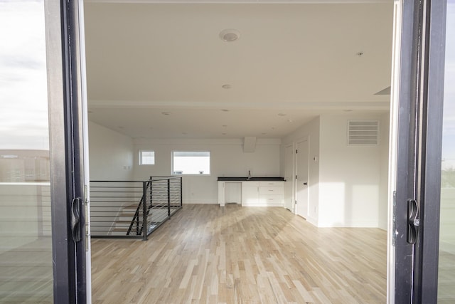 unfurnished room with light wood-type flooring, visible vents, and baseboards