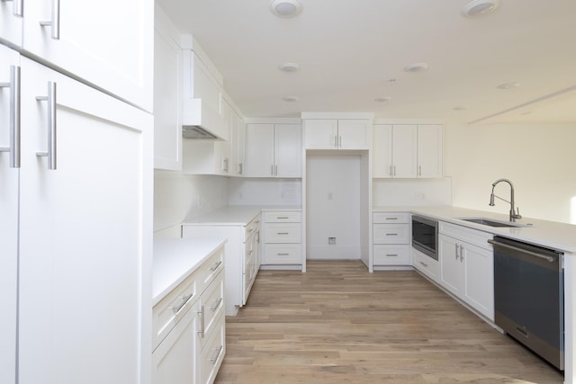 kitchen with stainless steel appliances, tasteful backsplash, light wood-style floors, white cabinets, and a sink