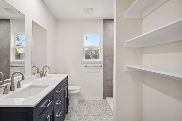 full bath featuring toilet, tile patterned flooring, double vanity, and a sink