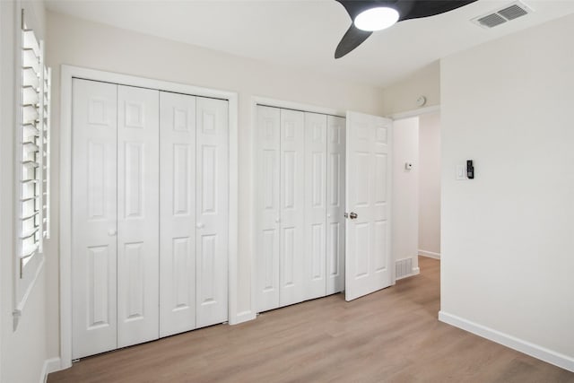 unfurnished bedroom featuring light wood-type flooring, two closets, and visible vents