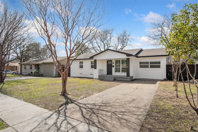 ranch-style house featuring an attached garage, fence, driveway, roof with shingles, and a front lawn