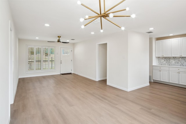 unfurnished living room with light wood finished floors, visible vents, and baseboards