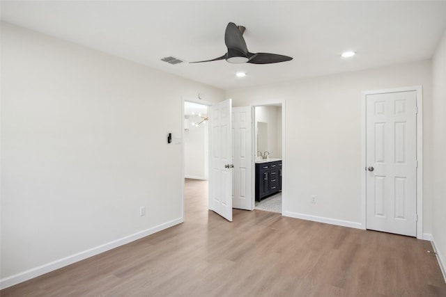 unfurnished bedroom featuring light wood-style floors, ensuite bath, visible vents, and baseboards