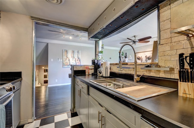 kitchen with ceiling fan, a sink, light floors, dark countertops, and crown molding