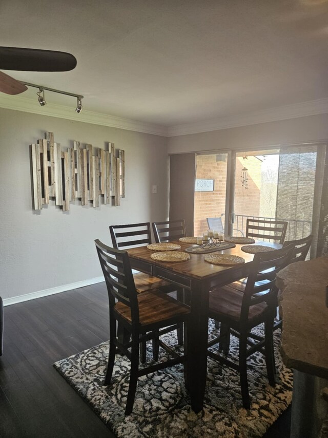 dining area featuring dark wood-style floors, rail lighting, crown molding, and baseboards