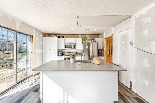 kitchen featuring stainless steel appliances, white cabinetry, a sink, and wood finished floors