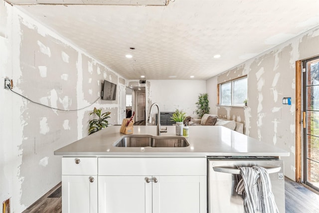 kitchen with wood finished floors, a sink, white cabinetry, light countertops, and stainless steel dishwasher