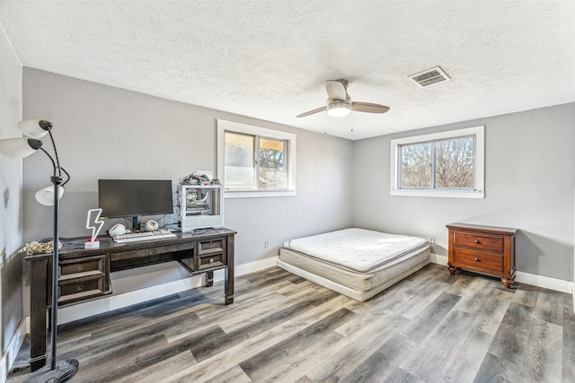 bedroom featuring multiple windows, wood finished floors, and visible vents