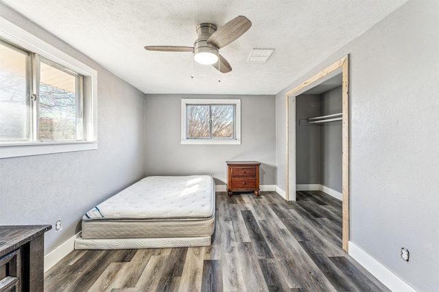 bedroom featuring visible vents, baseboards, wood finished floors, a textured ceiling, and a closet