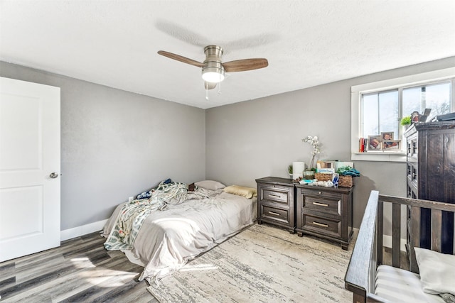 bedroom with a textured ceiling, wood finished floors, a ceiling fan, and baseboards