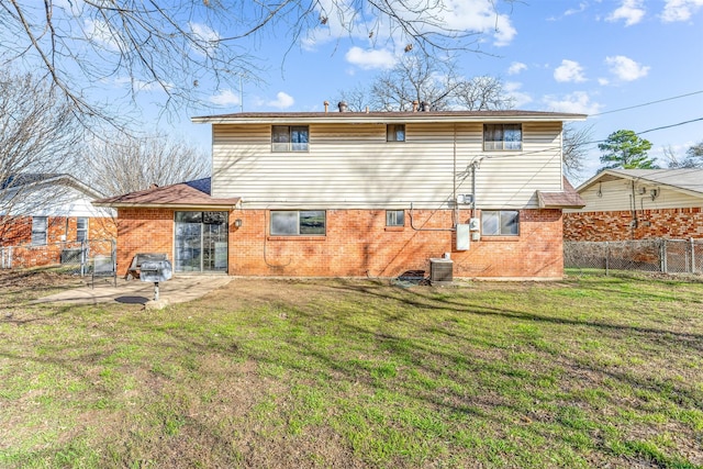 back of property with brick siding, a lawn, cooling unit, and fence