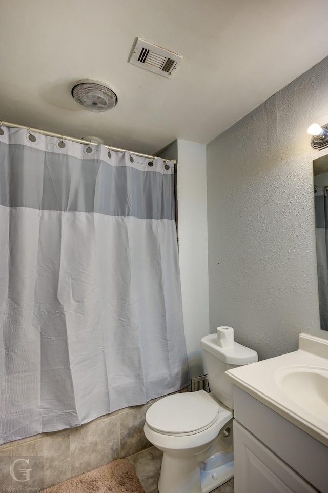 full bath featuring curtained shower, visible vents, a textured wall, and vanity