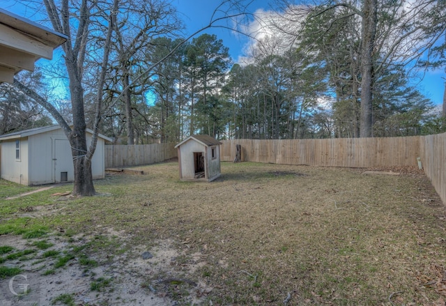 view of yard with a storage shed, an outbuilding, and a fenced backyard