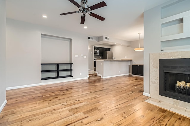 unfurnished living room featuring light wood-type flooring, visible vents, a fireplace, and baseboards