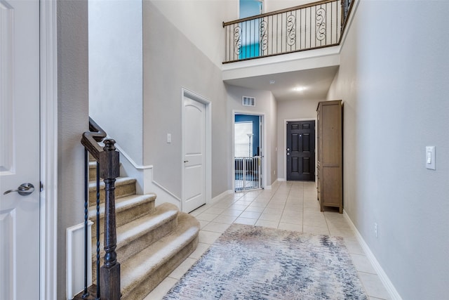 entryway with visible vents, stairway, baseboards, and light tile patterned floors