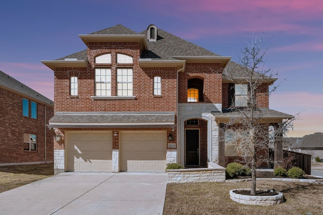 view of front of house featuring a garage, brick siding, driveway, stone siding, and roof with shingles