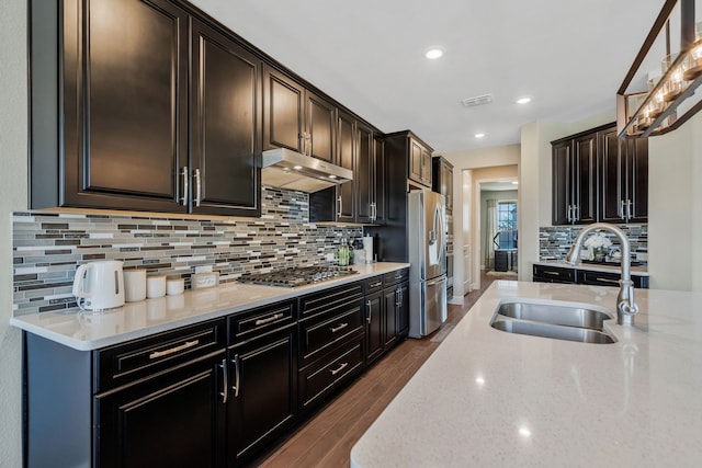 kitchen featuring visible vents, dark wood-style floors, appliances with stainless steel finishes, under cabinet range hood, and a sink