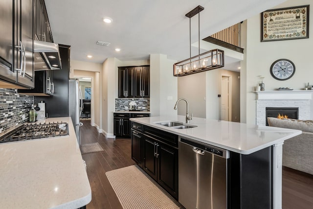 kitchen featuring stainless steel appliances, dark wood-style flooring, a sink, visible vents, and a lit fireplace