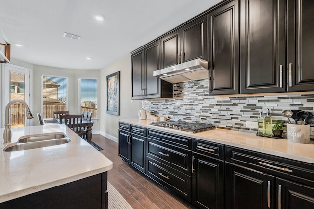 kitchen with under cabinet range hood, stainless steel gas cooktop, a sink, visible vents, and dark wood-style floors