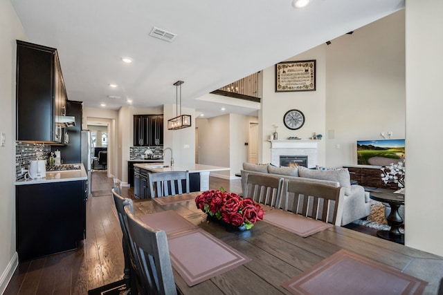 dining room featuring a glass covered fireplace, dark wood-style flooring, visible vents, and recessed lighting