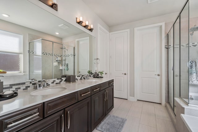 bathroom featuring visible vents, a sink, a shower stall, and double vanity