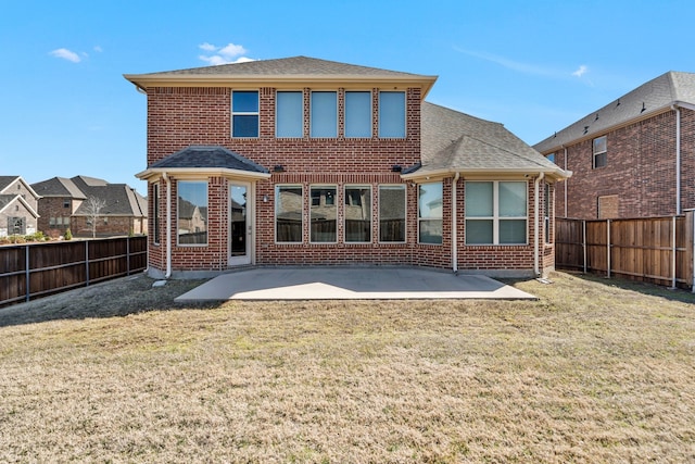 back of property featuring brick siding, a yard, and a fenced backyard