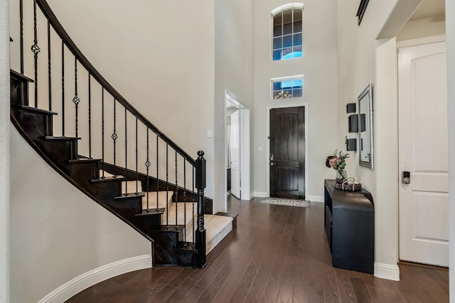 entrance foyer featuring wood finished floors, a towering ceiling, and baseboards