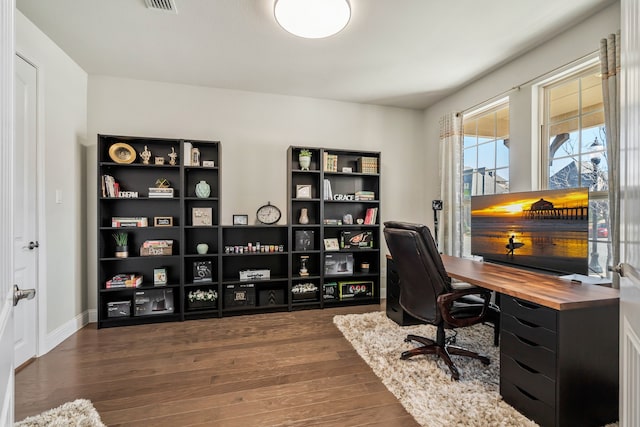 home office with wood finished floors, visible vents, and baseboards