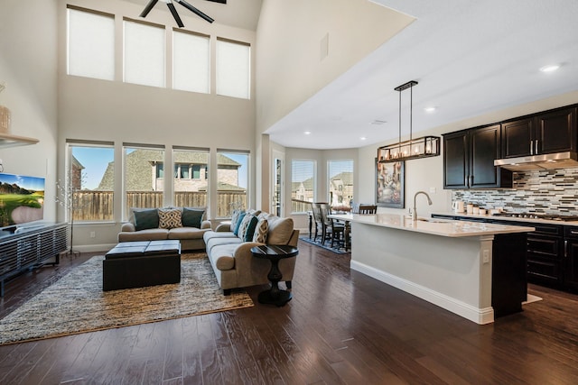 living room featuring dark wood-type flooring, recessed lighting, a high ceiling, and baseboards