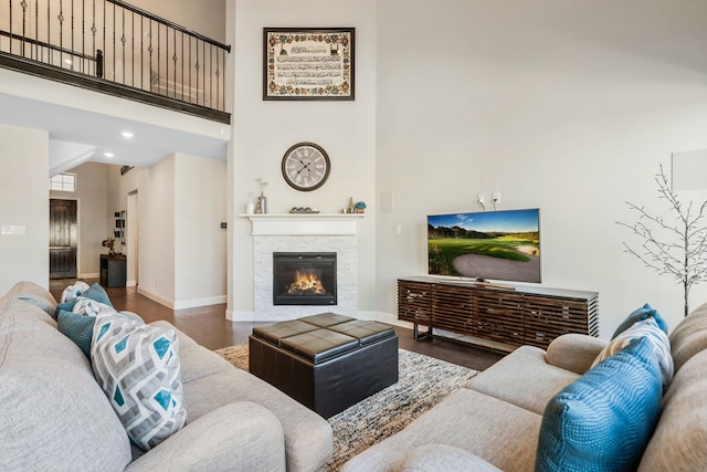 living room with baseboards, a fireplace, a high ceiling, and wood finished floors