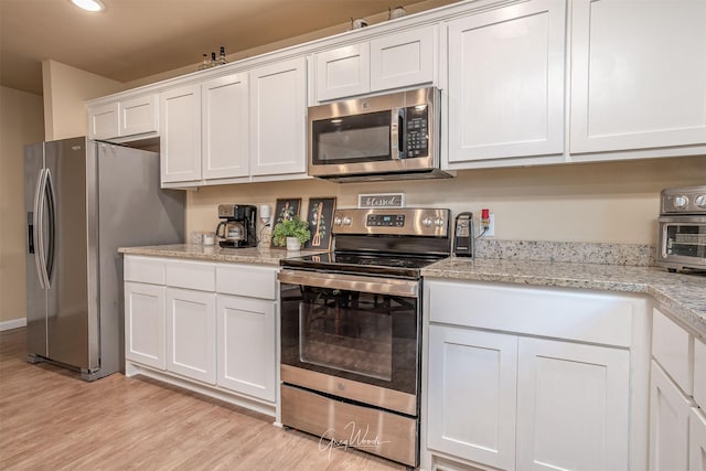 kitchen featuring light stone counters, recessed lighting, white cabinets, appliances with stainless steel finishes, and light wood finished floors