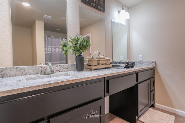 full bath featuring double vanity, visible vents, baseboards, wood finished floors, and a sink