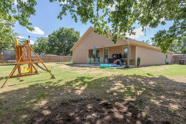 rear view of house featuring a playground, a fenced backyard, a lawn, a trampoline, and a patio area