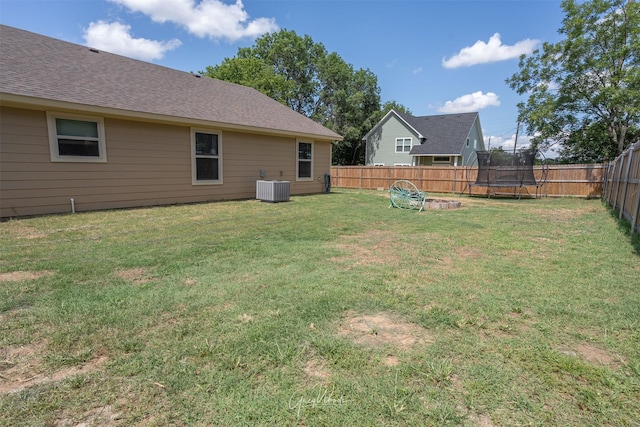 view of yard with a fenced backyard, a trampoline, and central AC unit