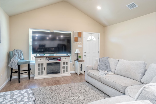 living area featuring baseboards, visible vents, lofted ceiling, wood finished floors, and recessed lighting