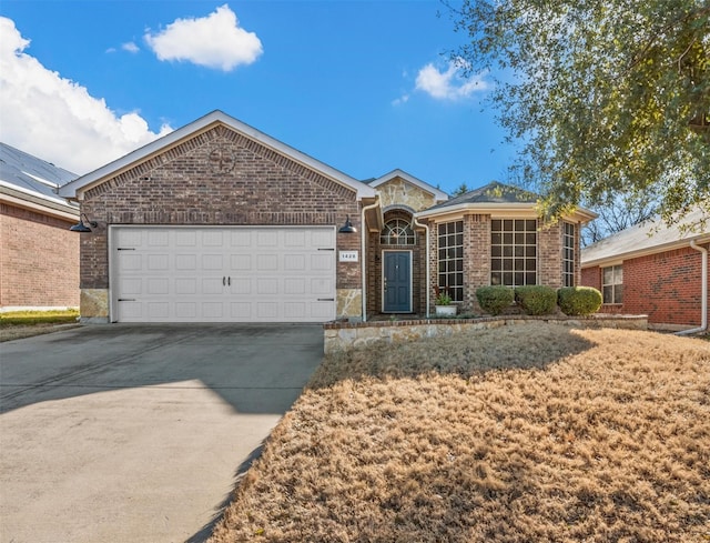 ranch-style house featuring an attached garage, stone siding, concrete driveway, and brick siding