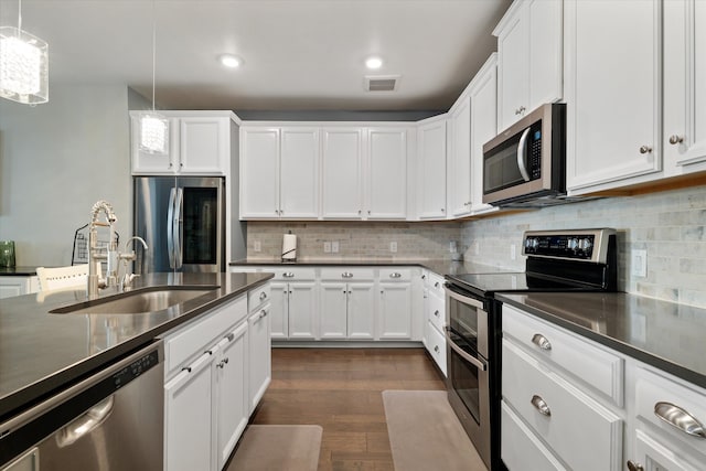 kitchen with dark countertops, visible vents, appliances with stainless steel finishes, dark wood-style floors, and a sink