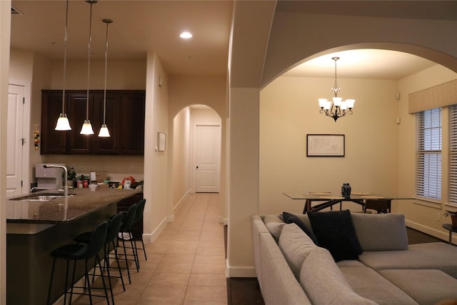 living area featuring arched walkways, recessed lighting, light tile patterned flooring, a chandelier, and baseboards