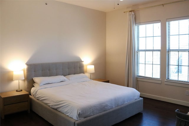 bedroom with multiple windows, baseboards, and dark wood-type flooring