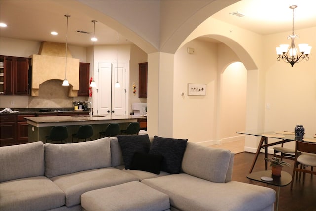 living room with dark wood-style floors, a notable chandelier, recessed lighting, visible vents, and baseboards