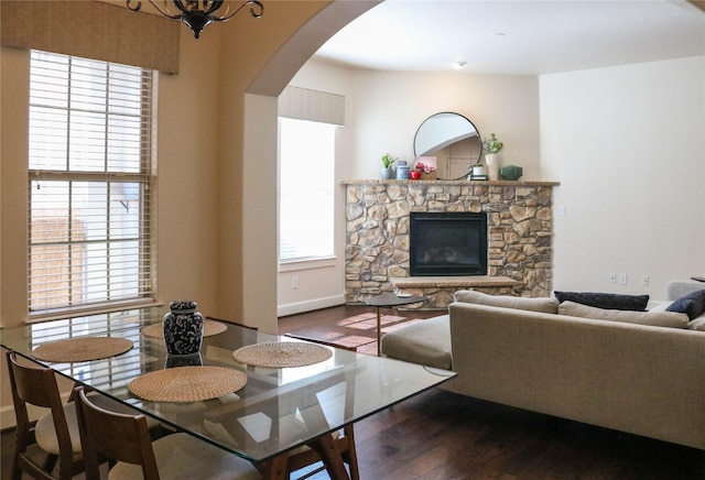 dining area featuring a wealth of natural light, a fireplace, arched walkways, and wood finished floors