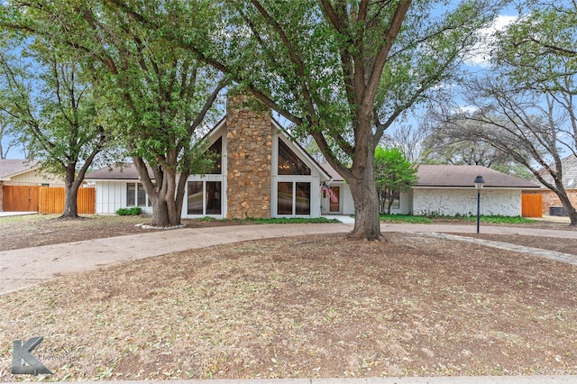 mid-century inspired home featuring stone siding and fence