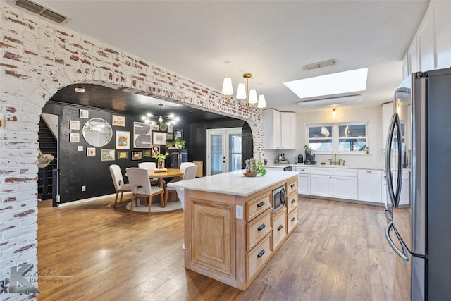 1258 Canterbury Dr, Abilene, TX 79602 - kitchen featuring stainless steel appliances, arched walkways, a skylight, light wood-style floors, and white cabinetry