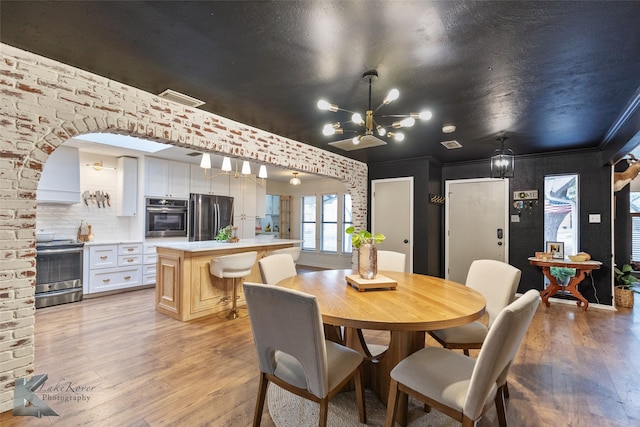 dining area with light wood finished floors, visible vents, ornamental molding, and a notable chandelier