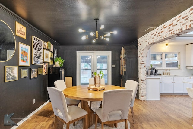 1258 Canterbury Dr, Abilene, TX 79602 - dining room with a chandelier, light wood-style floors, french doors, crown molding, and arched walkways