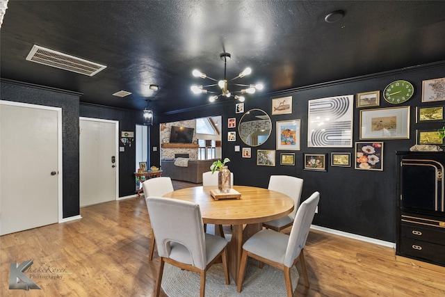 dining space featuring crown molding, visible vents, a notable chandelier, and wood finished floors